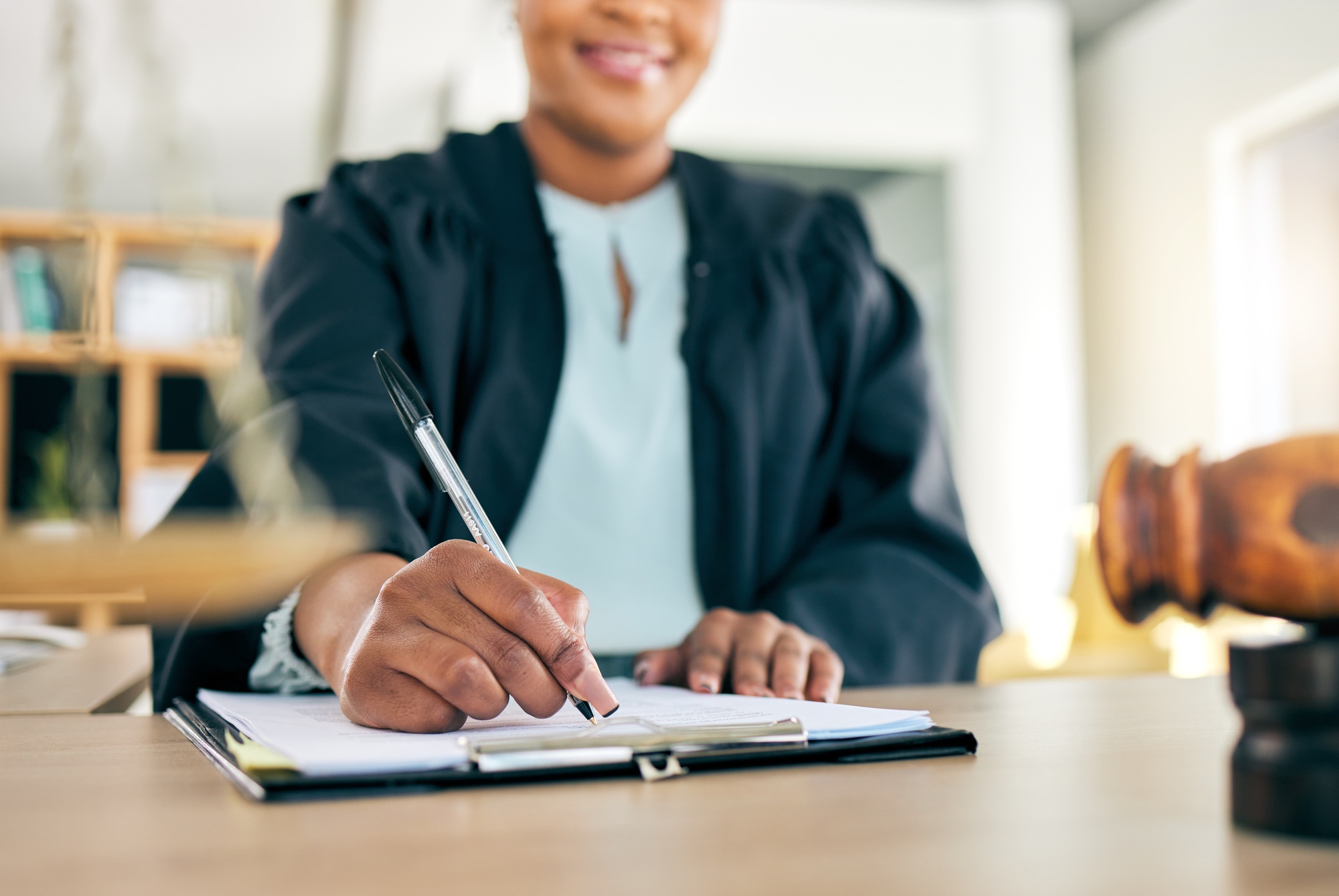 Legal, scale and hands of black woman lawyer writing for an investigation document or criminal case